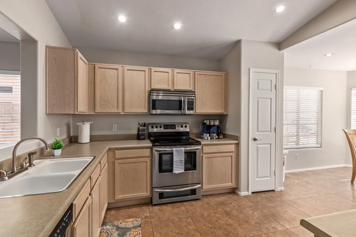A modern kitchen equipped with stainless steel appliances, a central island for food prep or informal dining, a window that allows natural light to flood in, and a decorative rug anchoring the space. The layout encourages cooking together and makes it easy for everyone to join in.