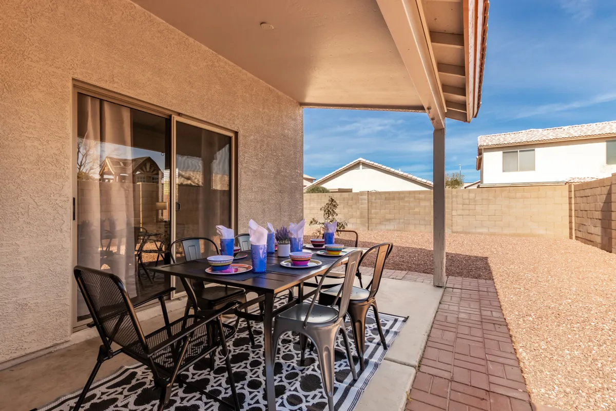 This image showcases a cheerful outdoor dining scene featuring a table with chairs, decorative table settings, and an outdoor rug. The scene is clearly set up for al fresco meals and gatherings, with a welcoming and festive atmosphere.