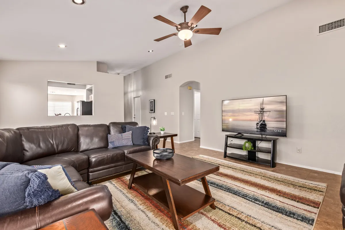 A cozy family living room with a leather sofa, coffee table, television, and a comfortable rug. The image captures moments of relaxing, watching TV, and socializing—ideal for unwinding together after community events.
