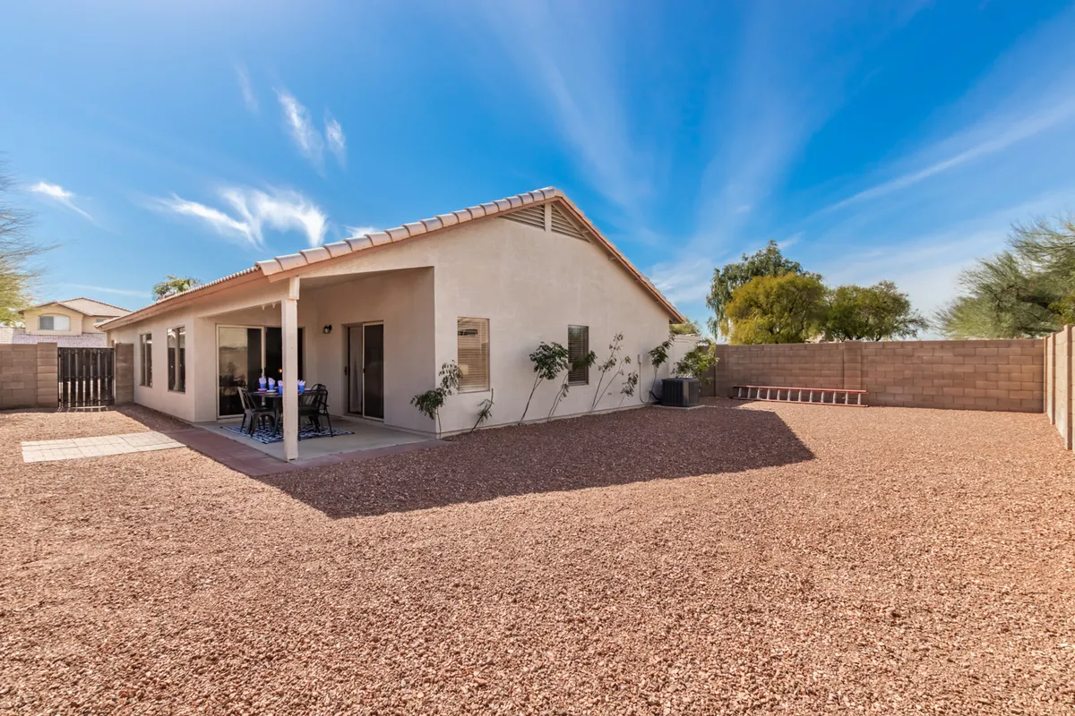 A relaxed backyard view featuring the house exterior, patio area, and thoughtful landscaping. The patio is spacious, enclosed, and well-suited for gatherings or enjoying a quiet cup of coffee in the sun.
