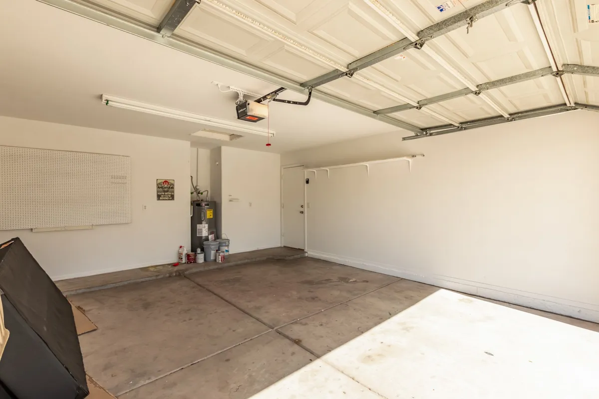 A practical garage space with a visible garage door, wall-mounted pegboard for tools or storage, lighting, and a door that leads directly into the home. The space is clean, organized, and ready for secure parking or extra storage needs.